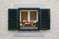 window in the wall with blinders open and a vase with flowers