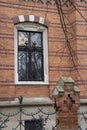 A window in the wall of a house made of multi-colored bricks with a beautiful forged lattice and fence elements Royalty Free Stock Photo