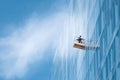 Window washer on modern skyscraper. Blue sky backdrop. Illustrates precision, cleanliness, urban development, and skilled labor. Royalty Free Stock Photo