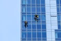 Window washers cleaning the glass facade of a modern building, high risk work