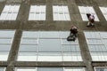 Window washers on top. Two workers hung ropes wash windows on high-rise