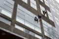 Window washers on top. Two workers hung ropes wash windows on high-rise