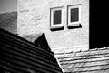 Old brick wall with 2 windows and different tile roofs in black and white Royalty Free Stock Photo