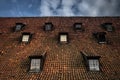 Symmetrical roof windows. Red tile. Seven windows on blue sky background.