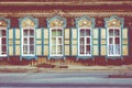 Window with the wooden carved architrave in the old wooden house in the old Russian town. Irkutsk