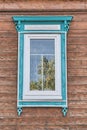 Window with wooden carved turquoise white architraves on brown plank facade of old house. Royalty Free Stock Photo