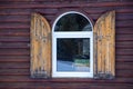 A window with wooden shutters against a cherry wood wall Royalty Free Stock Photo