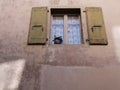 Window with wooden shutters and flowers in a flowerpot in the weathered wall of rustic house. Royalty Free Stock Photo