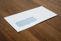 Windowed envelope lying on brown wood table