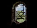 Windows of an ancient temple, in the wall of red brick, in the form of an arch. The hole in the wall is sealed with metal bars