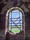 Windows of an ancient temple, in the wall of red brick, in the form of an arch. The hole in the wall is sealed with metal bars