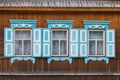 3 windows with beautiful blue platbands, shutters and white curtains in a wooden house Royalty Free Stock Photo