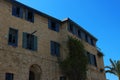 Windows with blue wooden shutters on the facade of the house are made of yellow Israeli stone. Royalty Free Stock Photo