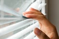 Windows jalousie. woman peeking through window blinds. Male hand separating slats of venetian blinds with a finger to Royalty Free Stock Photo