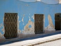 Windows with metal grid on old crumbling blue wall