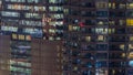 Windows of the multi-storey building of glass and steel lighting inside and moving people within Royalty Free Stock Photo