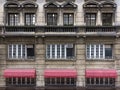 Windows in old concrete building in the center of the city with red awning