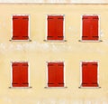 Windows with red wooden shutters on a weathered wall, closeup background. Royalty Free Stock Photo