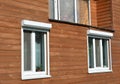 Windows with rolling shutter protection on the wooden house facade