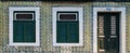 Windows with shutters and door in front of rustic old house with green yellow azulejo tiles walls in Lisbon