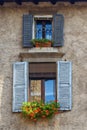 Windows with shutters on facade of residential building with flowers on it. Bergamo. Italy Royalty Free Stock Photo