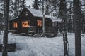 Warm glowing windows from a wooden cabin in the wintery forest Royalty Free Stock Photo