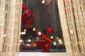 On the windowsill against the city lights hanging and standing a small vase in the shape of a heart