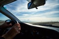 Windscreen view of nature, road, sky and hand of man on the steering wheel in a spring, summer or autumn day. The concept of a