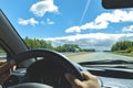 Windscreen view of nature road sky hand of man on the steering wheel in a spring summer or autumn day Soft focus