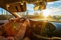 Windscreen view of nature, road, sun and hand of woman on the steering wheel in a spring, summer or autumn day. The concept of a