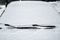 windshield with wipers of a snow-covered car.