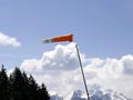 Windsock flying horizontaly, indicating strong wind and the direction of the wind with sunny blue sky in the mountain Royalty Free Stock Photo