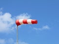 Windsock indicator of wind. Horizontally flying windsock ( wind vane ) with blue sky and white clouds in the background. Royalty Free Stock Photo