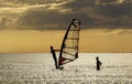 Windsurf training. The teacher explains to the student how to control the sail. Silhouettes in the rays of the setting sun