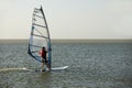 Windsurfer against the backdrop of the setting sun, on calm water, goes calmly along the sea, active recreation