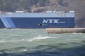 Windsurfer lifted into the air against the backdrop of a NYK Line ship above white caps beneath the Golden Gate Bridge. Editorial