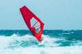 Windsurfer riding the wave with a red sail Royalty Free Stock Photo