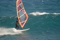 Windsurfer sailing next to a wave.