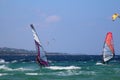 Windsurfers and kitesurfers planing over the emerald green water of Sardinia