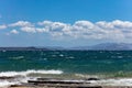 Stormy sea, waves splashing on rocks, blue sky with clouds background