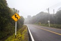 Windy forest road with a curve sign on a foggy day  at Doi Inthanon national park, Thailand Royalty Free Stock Photo