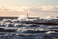 Windy late evening sunset view to Baltic sea lighthouse with large storm waves Royalty Free Stock Photo