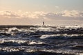 Windy late evening sunset view to Baltic sea lighthouse with large storm waves Royalty Free Stock Photo