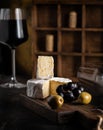 wine appetizer: cheese, olives and grapes are on the table next to a glass of red wine Royalty Free Stock Photo