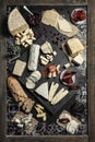 Wine appetizers set on the top view: cheese selection, bread sticks and prunes on the wood serving board background.