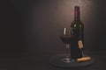 Wine bottle, glass with red wine and cork with corkscrew on dark wooden background. Celebration concept. Copy space Royalty Free Stock Photo