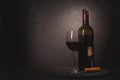 Wine bottle, glass with red wine and cork with corkscrew on dark wooden background. Celebration concept. Copy space. Toned Royalty Free Stock Photo