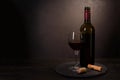 Wine bottle, glass with red wine and cork with corkscrew on dark wooden background. Celebration concept. Copy space Royalty Free Stock Photo