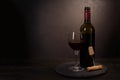 Wine bottle, glass with red wine and cork with corkscrew on dark wooden background. Celebration concept. Copy space Royalty Free Stock Photo