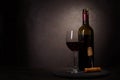 Wine bottle, glass with red wine and cork with corkscrew on dark wooden background. Celebration concept. Copy space Royalty Free Stock Photo